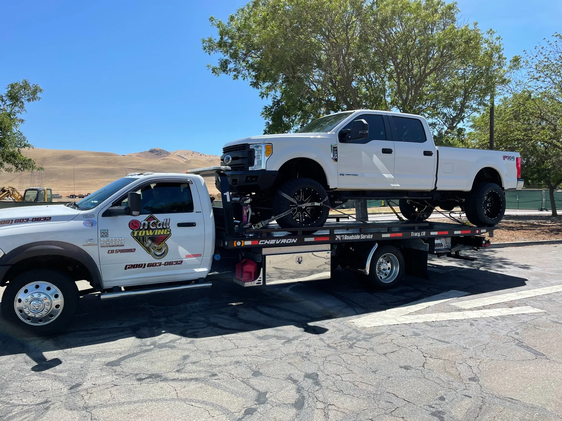 Lifted pickup truck transported on a flatbed by Oncall Towing INC
